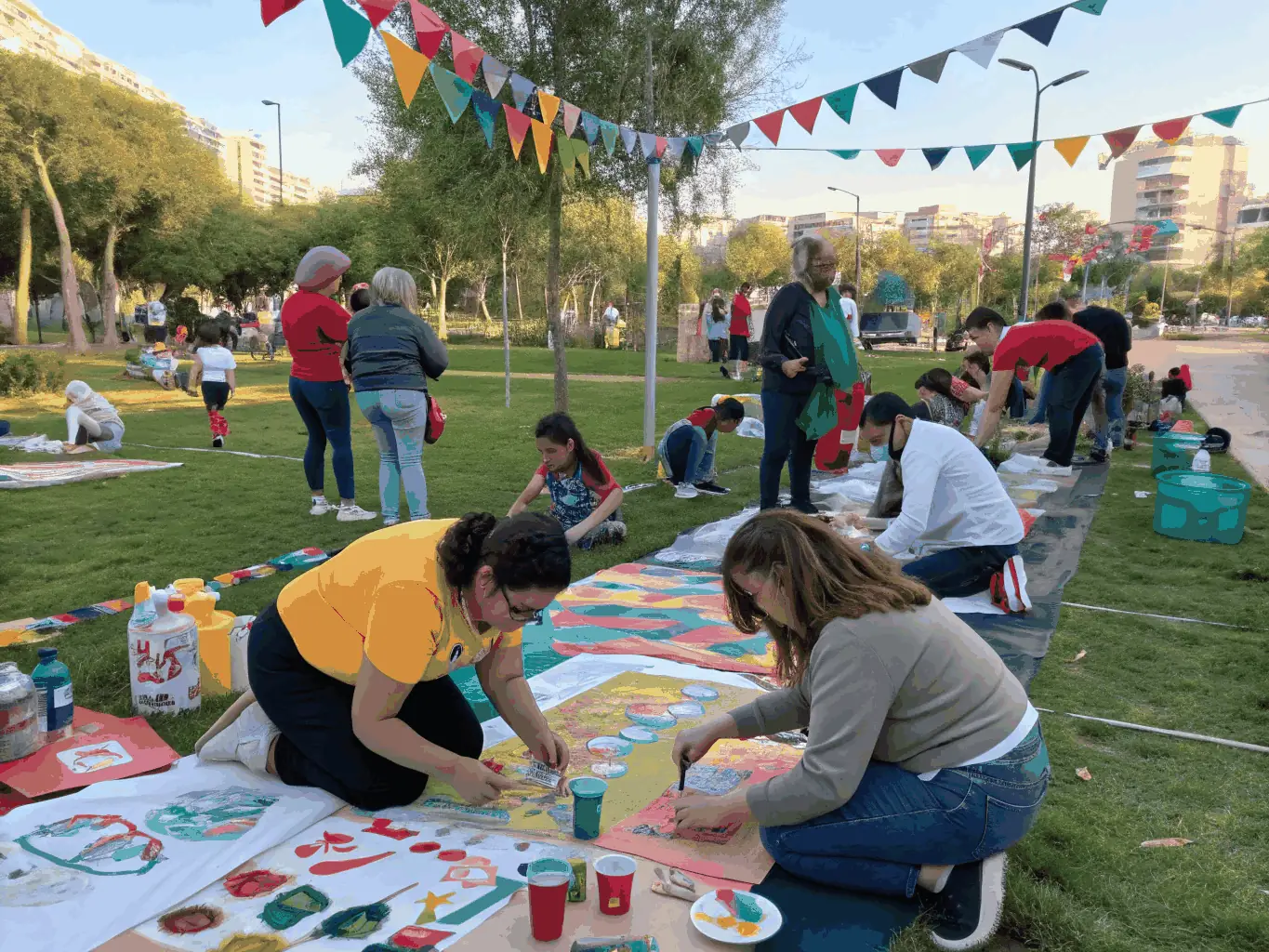 An image capturing a community engagement event organized by IMPASSYSTEM, featuring diverse participants engaging in an interactive art activity in a public space.